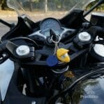 Llavero con forma de casco de motocross amarillo puesto en el encendido de una motocicleta deportiva.